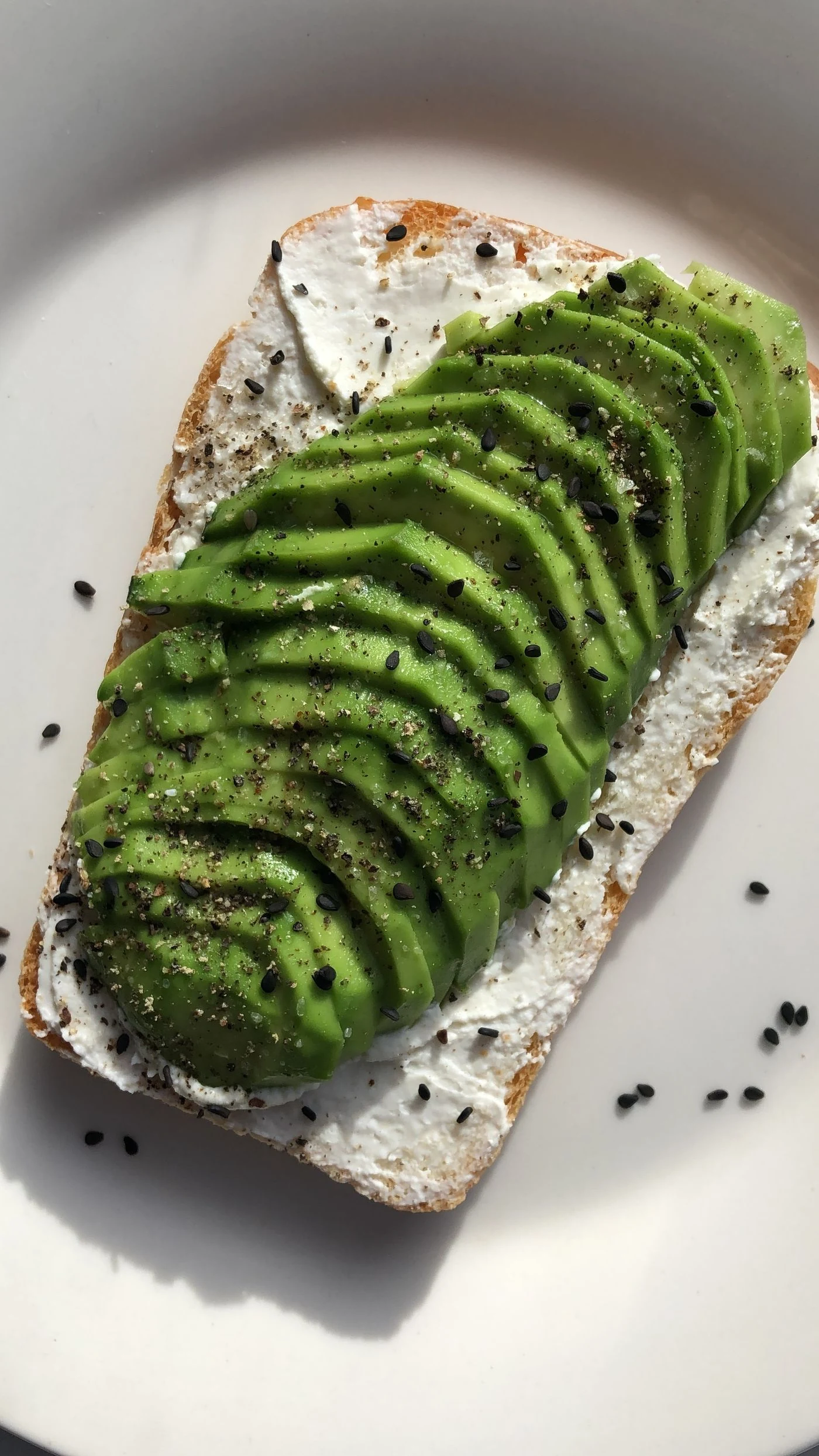 Cream-cheese toast with fanned avocado, black sesame seeds and black pepper