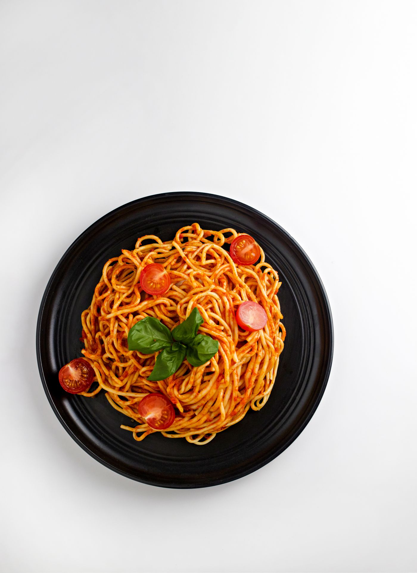 Burst tomato & basil spaghetti; spaghetti, red tomato sauce, cherry tomato pieces, fresh basil leaves