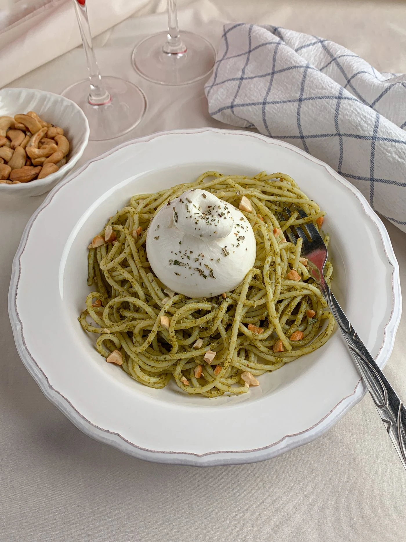 Green pesto spaghetti with a whole burrata ball, chopped cashews and dried herbs