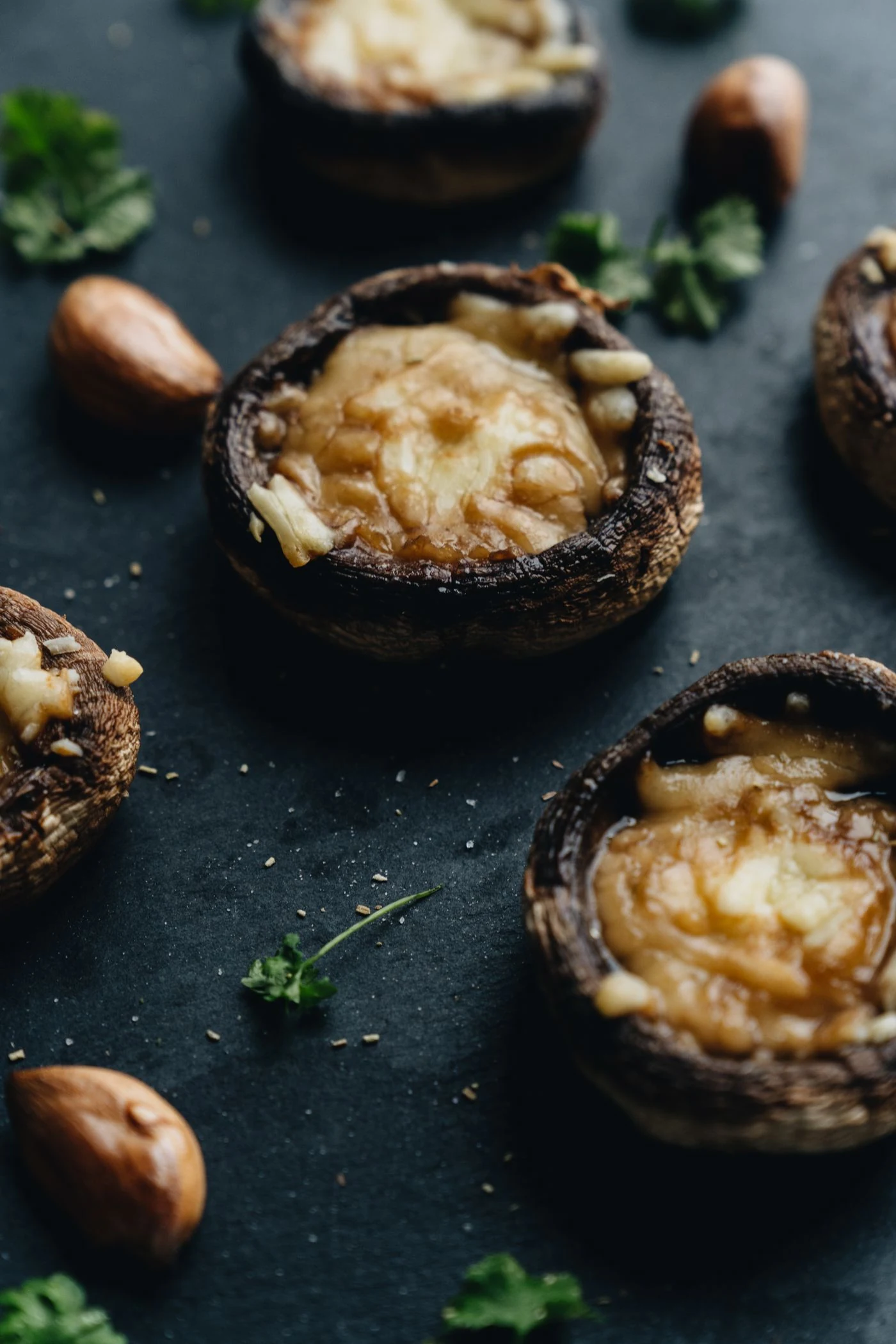 Roasted brown mushroom caps with melted cheese, parsley, almonds and garlic