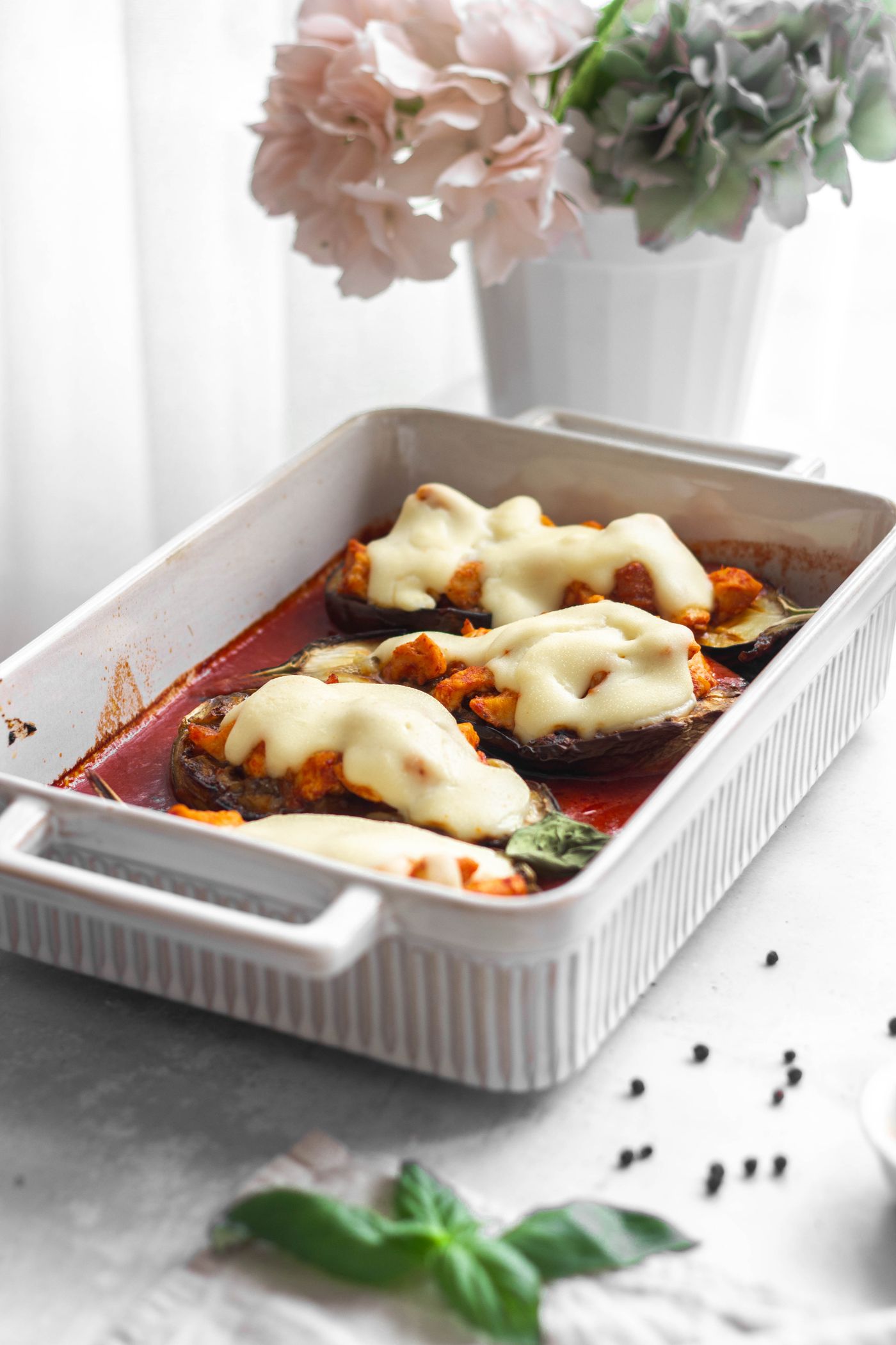 Tomato & mozzarella baked eggplant; eggplant halves, red tomato sauce, melted white cheese, fresh green herbs