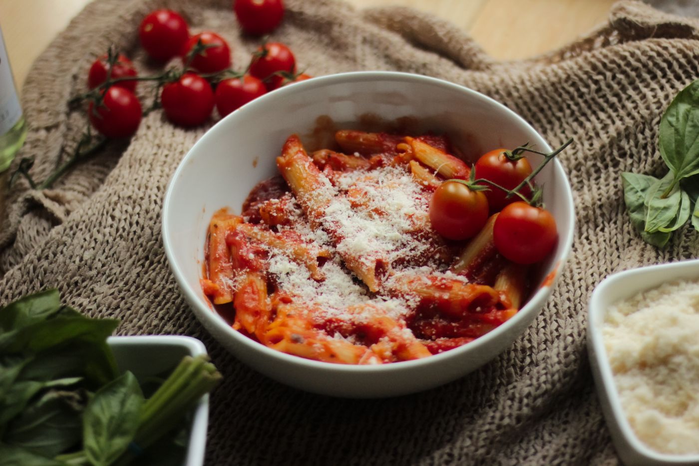 Cheesy tomato penne; penne pasta, red tomato sauce, grated Parmesan-style cheese, whole cherry tomatoes at bowl edge
