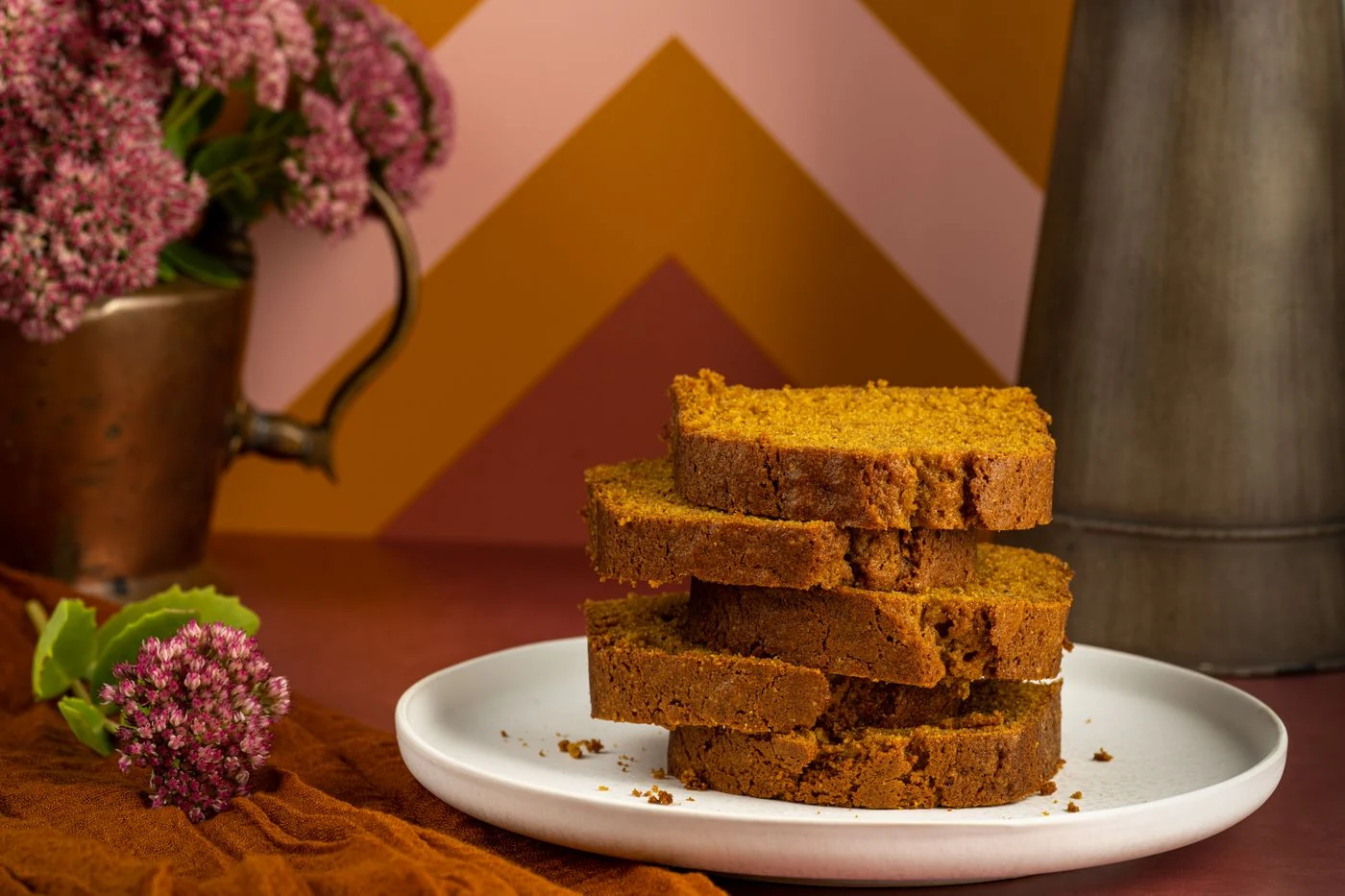 Plain cinnamon-spiced pumpkin loaf slices stacked on a white plate
