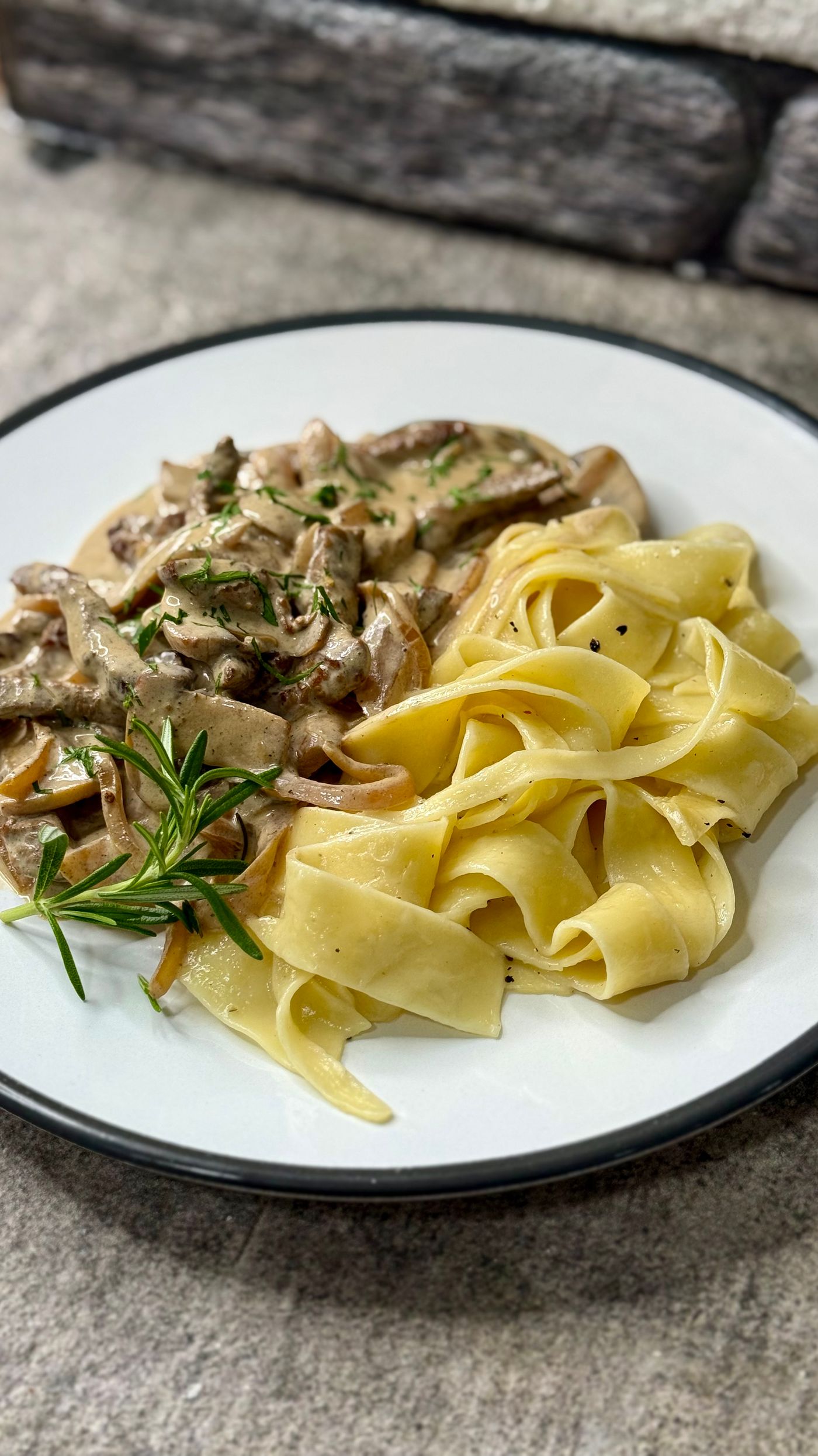 Creamy mushroom pappardelle; wide flat pasta ribbons, sliced mushrooms, creamy sauce, fresh rosemary sprig