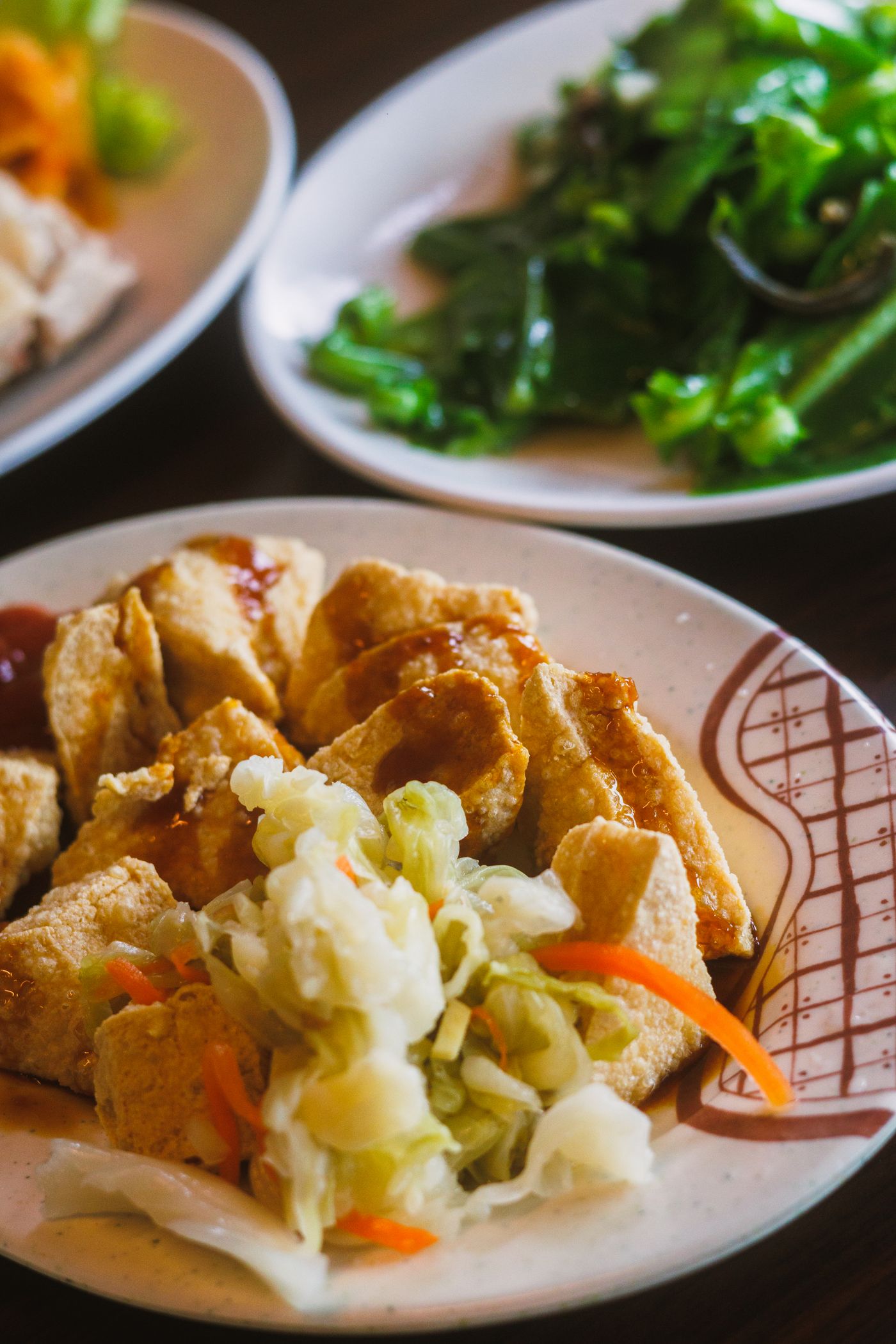 Crispy tofu with crunchy slaw; golden fried tofu pieces, pale shredded cabbage, carrot strips, green vegetable garnish