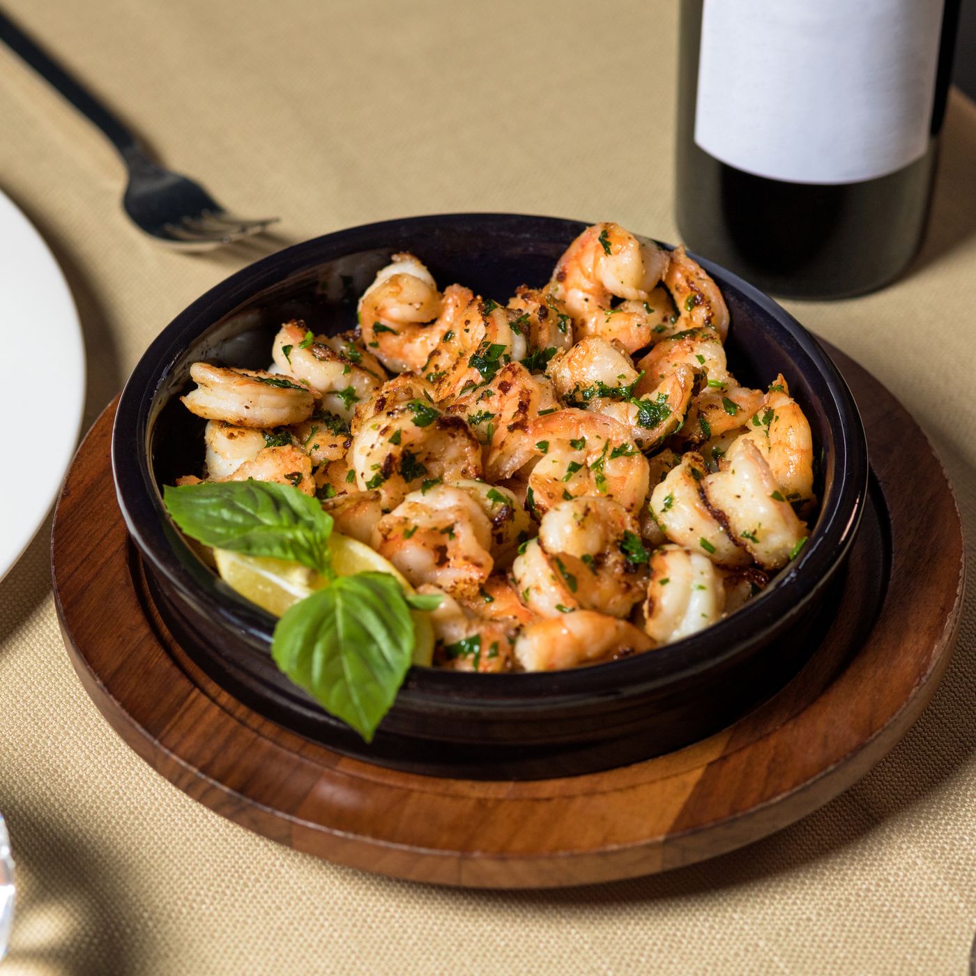 Garlic-herb shrimp skillet. cooked peeled shrimp; chopped leafy herbs; glossy golden sauce; whole basil leaves.