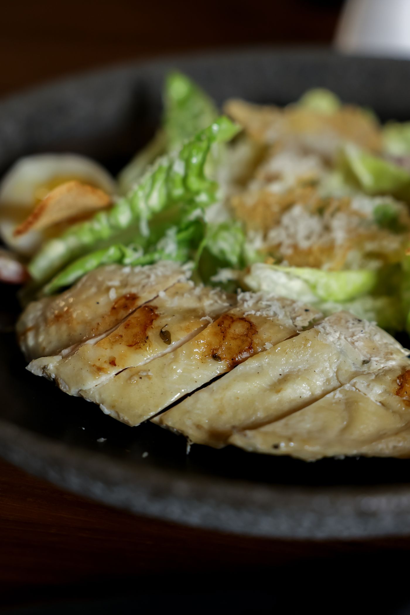 Grilled chicken Caesar salad. sliced grilled chicken breast; romaine-like lettuce; finely grated pale cheese; creamy dressing.