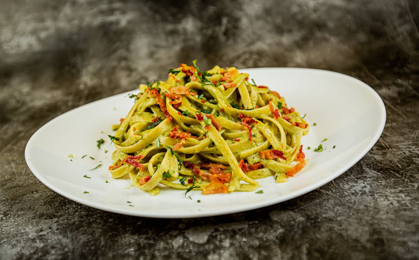 Sun-dried tomato pesto tagliatelle; flat pasta ribbons, green pesto coating, sun-dried tomato strips, finely chopped herbs