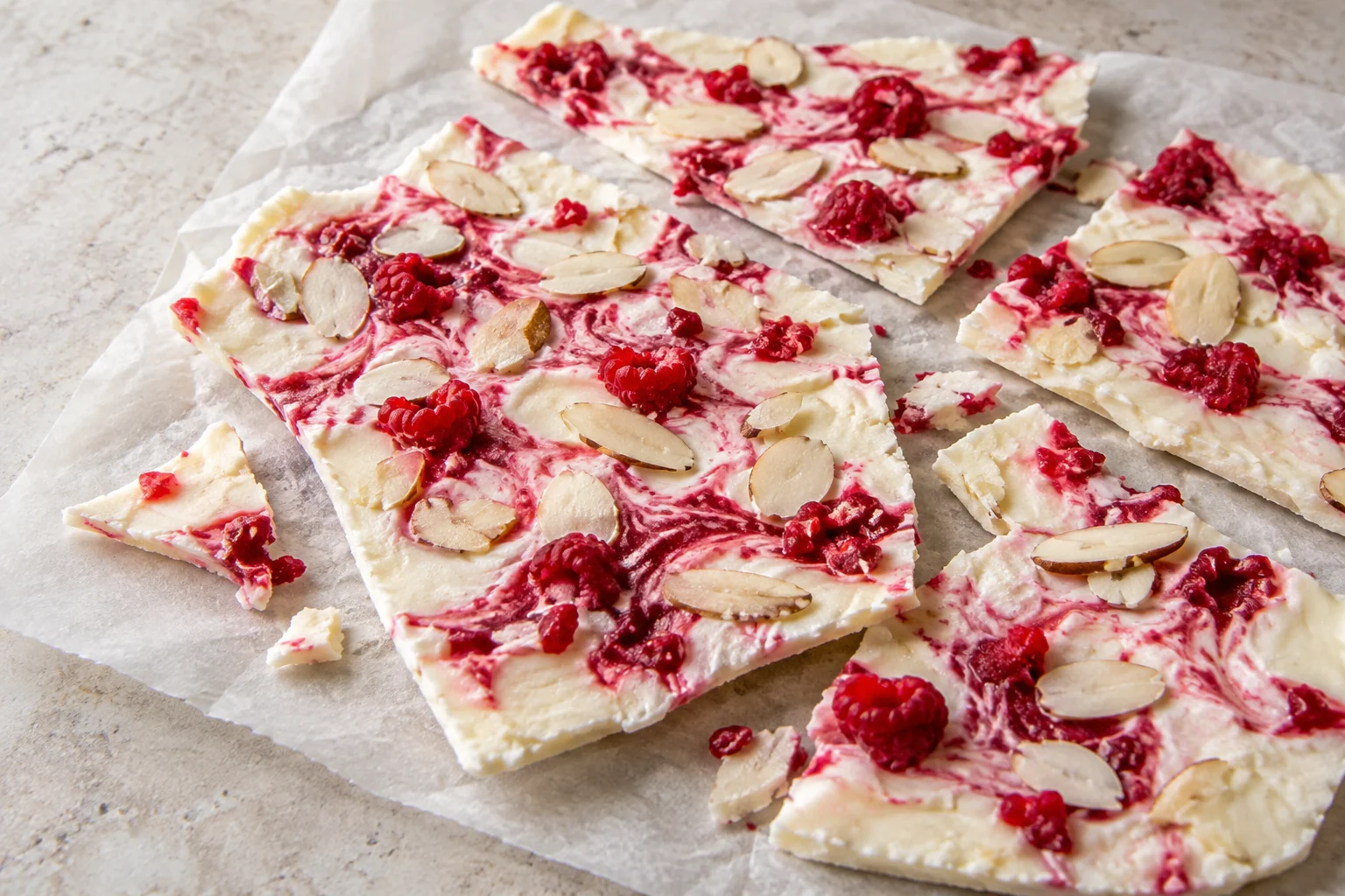A thin frozen sheet of whole-milk Greek yogurt with crushed raspberries, maple syrup and sliced almonds.