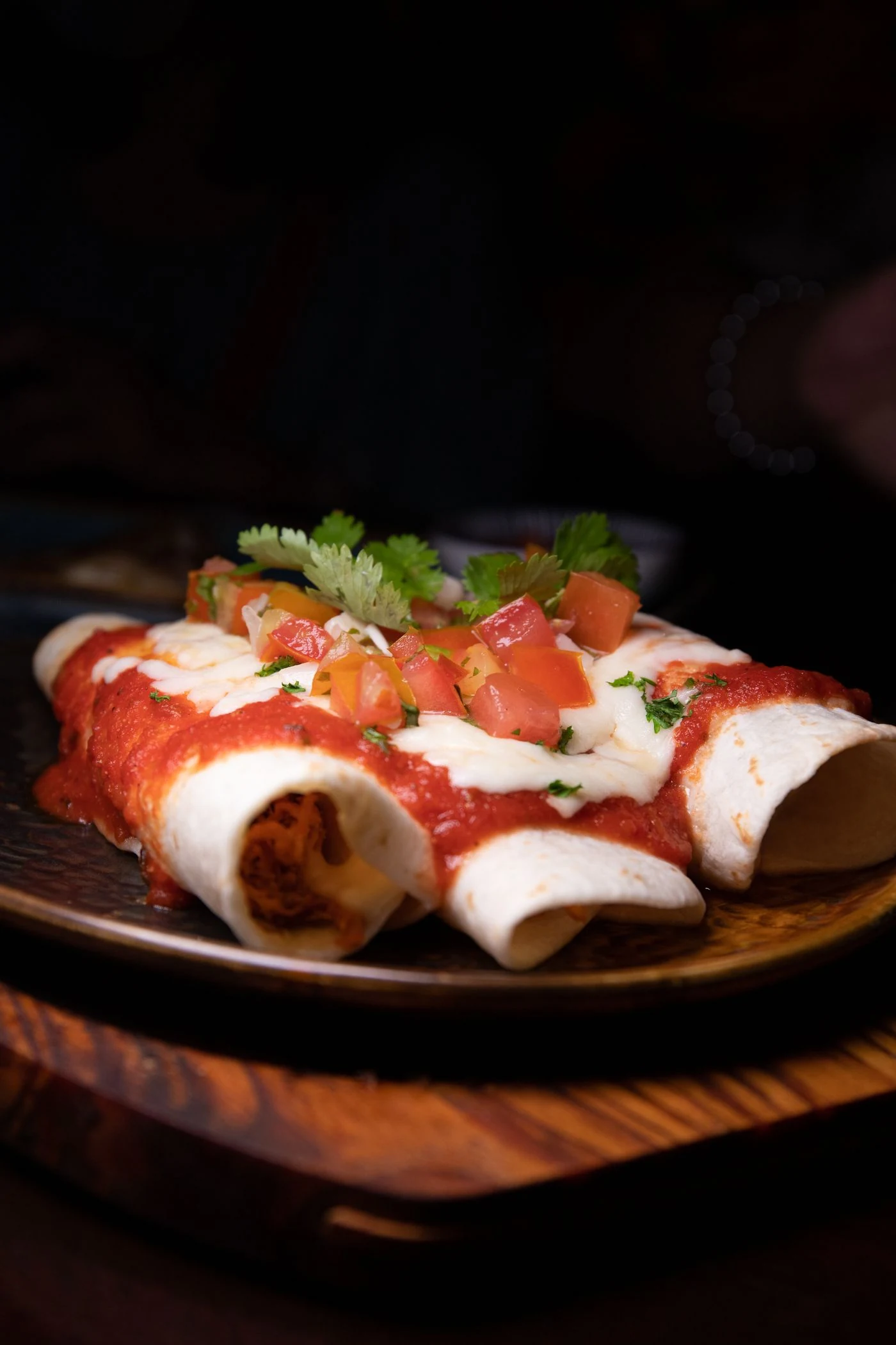 Chicken enchiladas with red sauce, white cheese and cream, diced tomato and cilantro