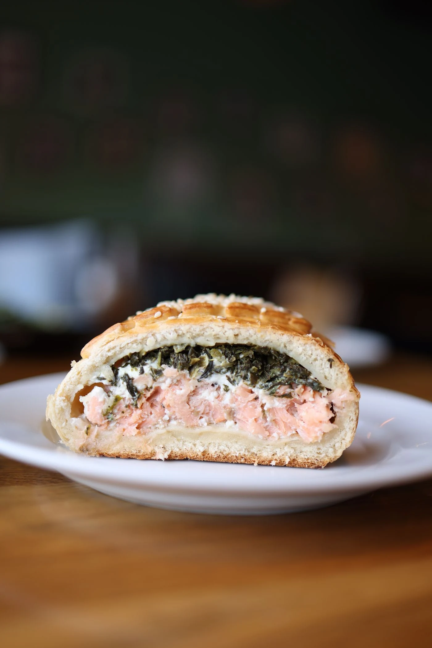 Cut-open sesame bread parcel with salmon, cream cheese and spinach