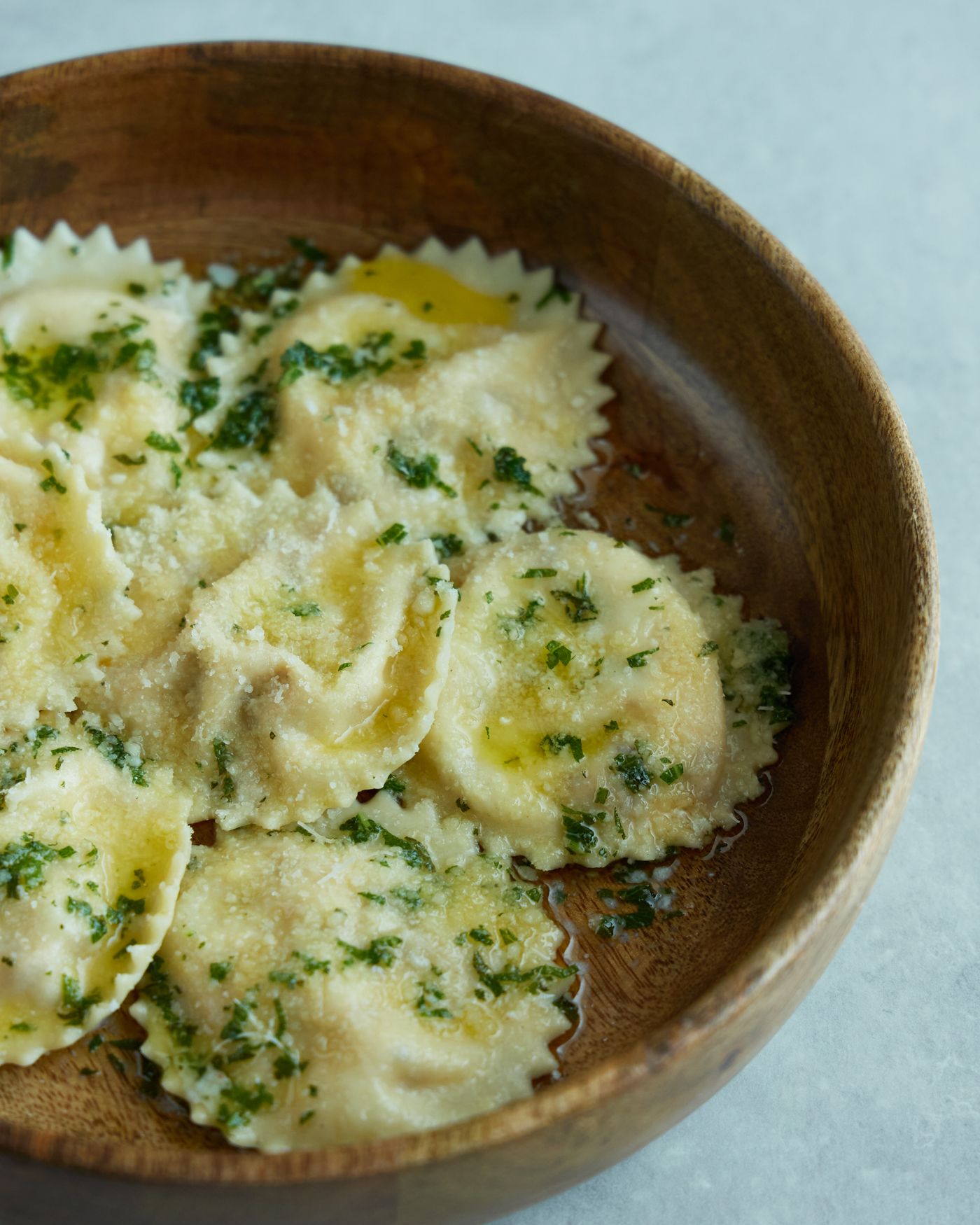 Spinach ravioli with Parmesan; round scalloped ravioli, chopped green spinach or herbs, grated hard cheese, light butter or olive oil sauce