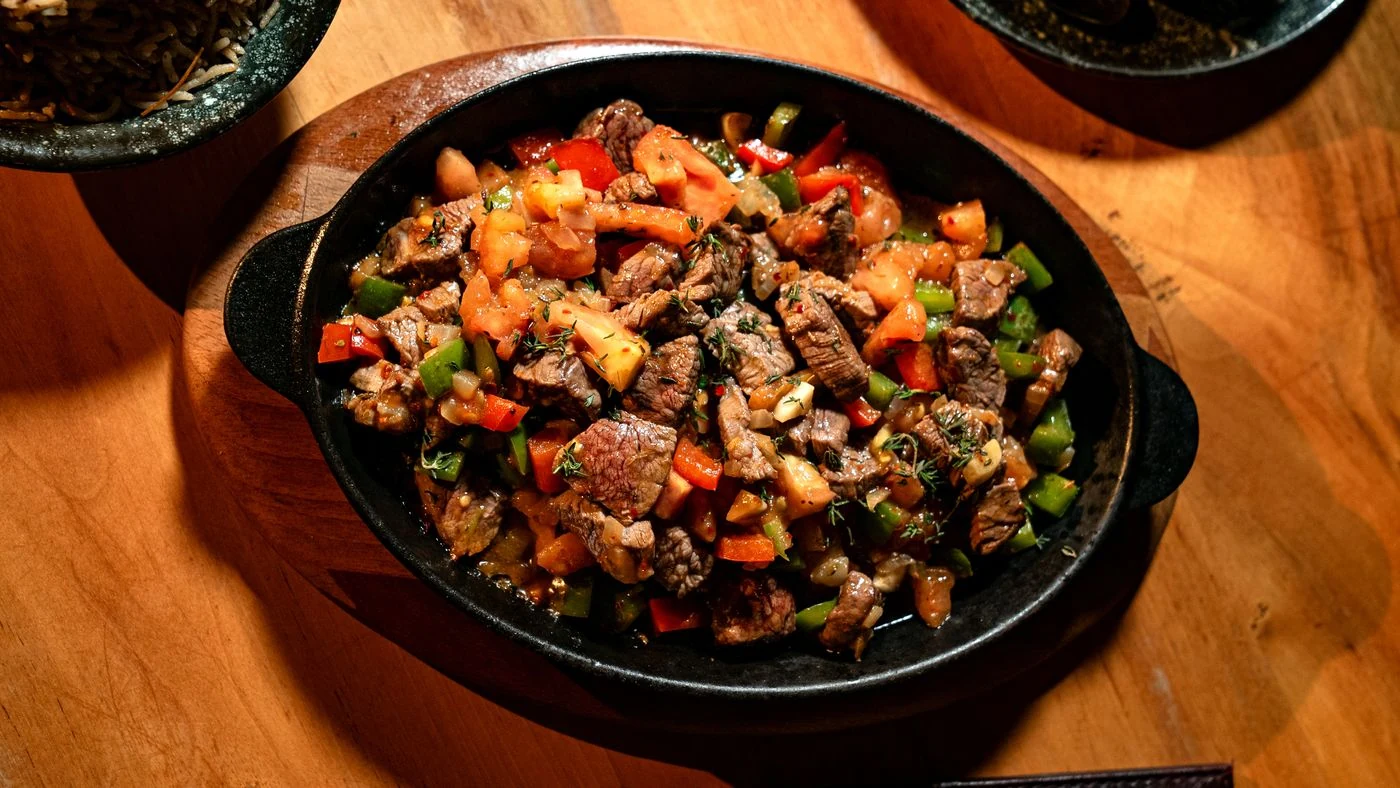 Skillet of beef bites with red and green peppers, tomatoes, onion and thyme